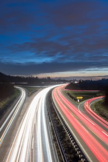Long-exposure highway at night with light trails and cloudy sky over the countryside, near