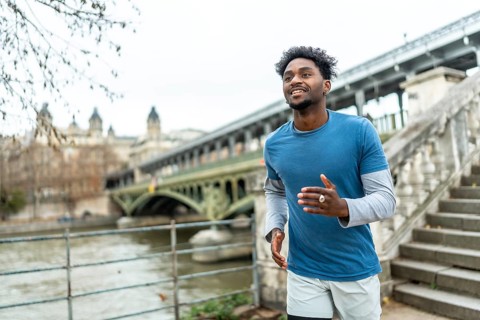 Young black man jogging along the seine in paris, training by the pont de bir hakeim with city