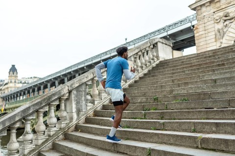 Athletic man training and exercising, running up stone stairs in paris, focusing on fitness and