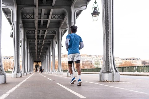 Man is jogging on a bridge in paris, focusing on urban fitness and a healthy lifestyle in the