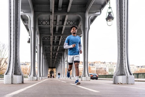 Young man smiling and running along the bir hakeim bridge in paris, engaging in urban sport and