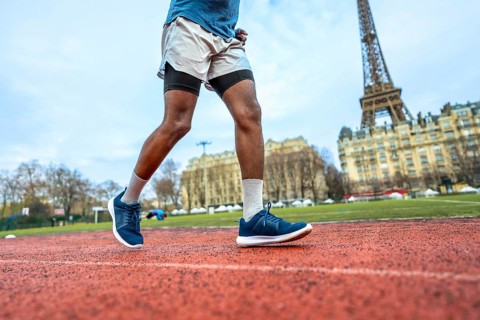Athlete running on a red track with the iconic eiffel tower and parisian buildings in the