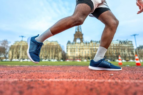Athletic person starting a sprint on a red running track, with the iconic eiffel tower and parisian