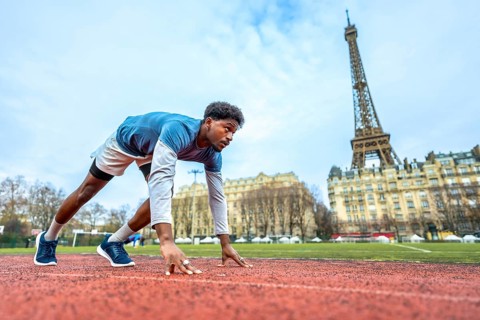 Young male athlete getting ready to run on an outdoor track in the heart of paris, focusing on the