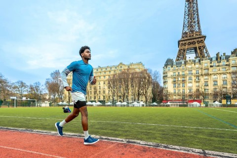 Young man training on a running track with the iconic eiffel tower and parisian buildings in the
