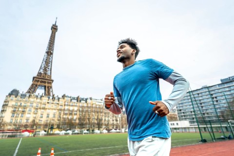 Young athletic black man training on a running track with the iconic eiffel tower and parisian