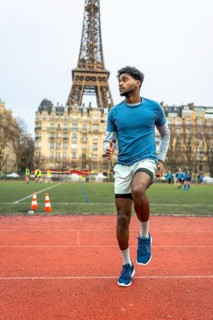 Young man doing speed drills on an outdoor running track, practicing high knees in paris with the