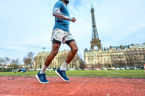 African american man sprinting on a red outdoor track in paris with the eiffel tower in the