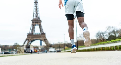 Man running on city street, elevating through a jump or stride, showcasing athleticism and an