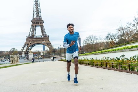 Young athletic black man jogging along paris streets, training outdoors near the eiffel tower,