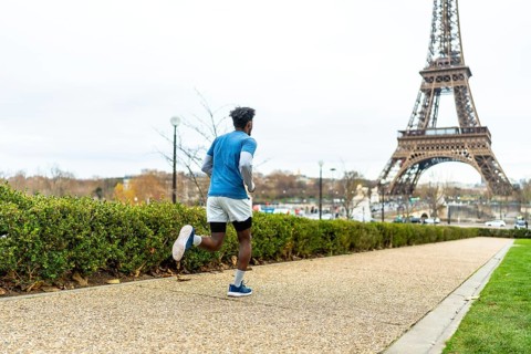 Man actively running along a path in paris, maintaining his fitness and enjoying urban sports with