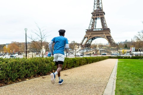 Young man exercising outdoors on a gravel path in paris, enjoying a fitness run with the iconic