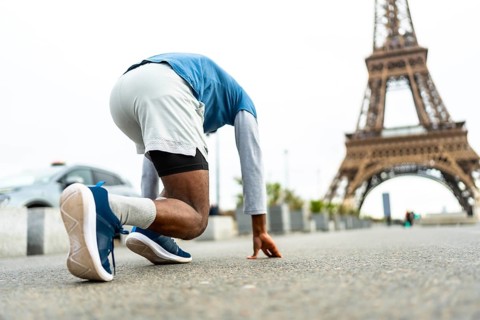 Athlete in starting position, poised for a run on an urban street, training for speed and