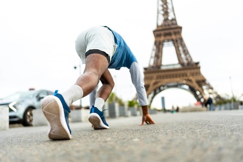 Male athlete in starting block position preparing for a sprint on a city street, with the iconic