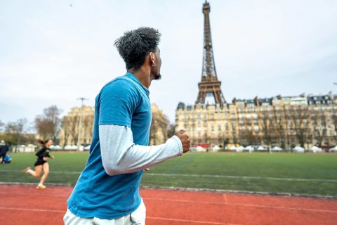 Young man training on a running track with the iconic eiffel tower and parisian buildings in the