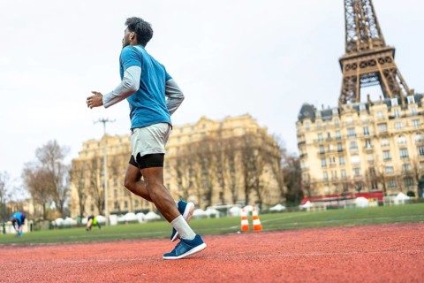 Black man engaging in physical activity, jogging for fitness and health on a tartan track in an