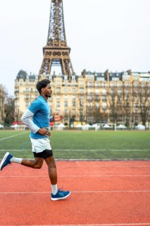 Young man running on an outdoor track in paris, training for fitness and endurance with the eiffel