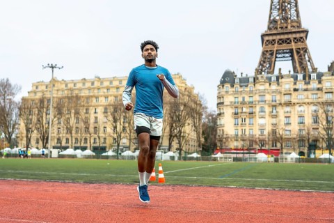 Young athletic man running on an outdoor track in paris, focusing on urban sport performance and
