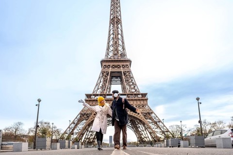 Happy young couple posing joyfully in front of the eiffel tower in paris, experiencing a romantic