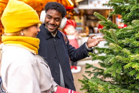 Smiling man pointing at a christmas tree while engaging in conversation with his partner at a