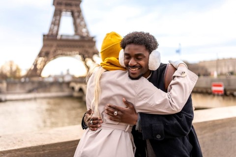 Happy young diverse couple hugging and smiling on a cold paris day, sharing warmth and romance with