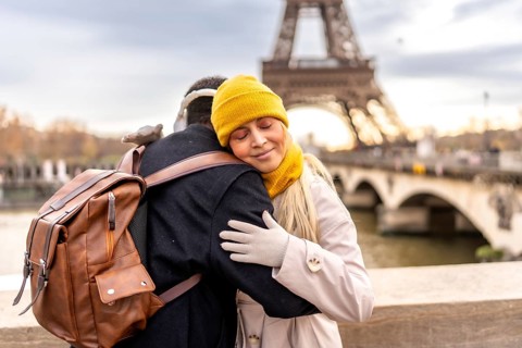 Young diverse couple embraces on a paris bridge, sharing a tender moment with the eiffel tower and