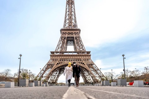 Couple walking hand in hand toward the eiffel tower in paris on a cloudy day, sharing a romantic