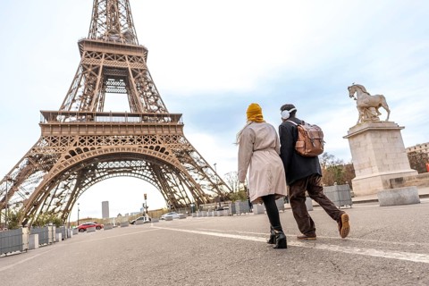 Young couple walking on a street, seen from behind, enjoying a romantic trip to the eiffel tower,