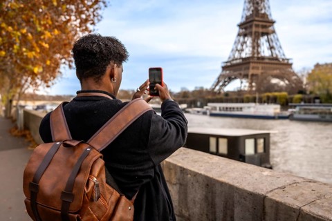 Tourist viewing and photographing the iconic eiffel tower from a bridge over the seine river in