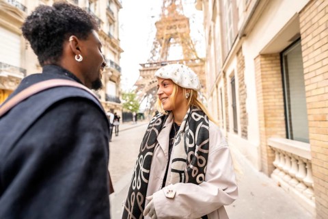 Happy diverse couple smiling and interacting on a parisian street with the eiffel tower in the