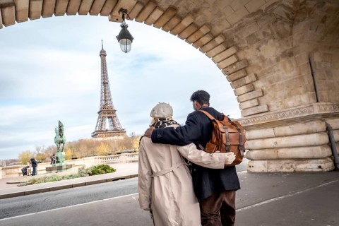 Couple embracing while walking under a stone arch bridge, enjoying a romantic travel sightseeing