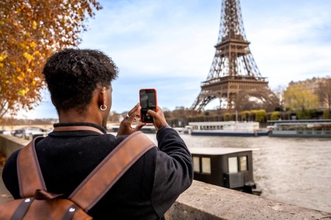 Traveler capturing a moment on smartphone while visiting the iconic eiffel tower in paris, engaging