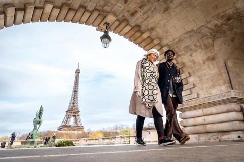 Young couple traveling through paris, france, walking under an archway with the iconic eiffel tower
