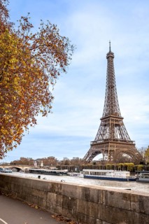 Iconic eiffel tower towering over the seine river in paris, with tour boats navigating the water