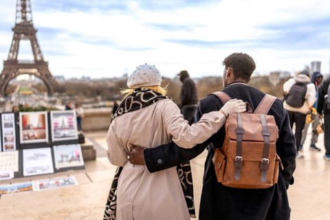 Diverse couple embracing each other viewing the iconic eiffel tower and cityscape, symbolizing