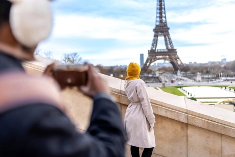 Tourist couple in paris enjoying the view as one photographs the eiffel tower and cityscape with a