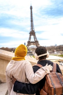 Loving couple standing with arms around each other, enjoying the view of the iconic eiffel tower in