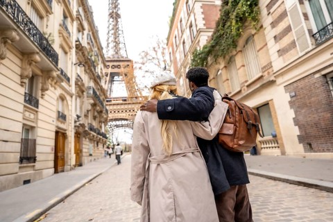 Diverse couple embracing in a romantic moment, walking through a charming parisian street with
