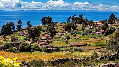Small huts and fields on terraces overlooking a large lake, countryside and farmhouses on Taquile