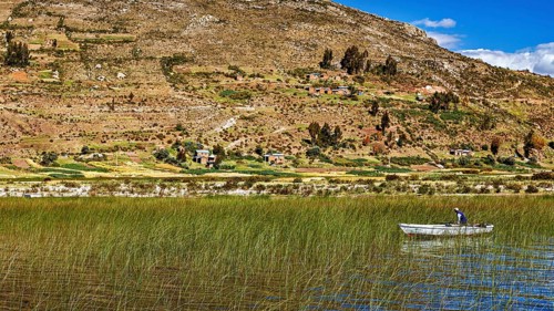 A boat on a reed lake surrounded by hills and a blue sky with clouds, the countryside and