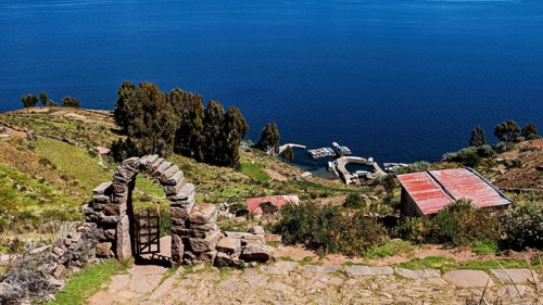 Stone archway with a view of the lake and shore. Surrounded by green hills and clear blue water,