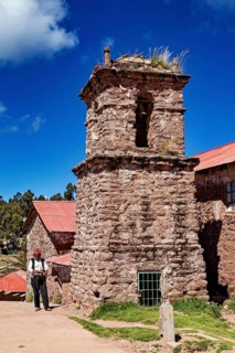 Old church tower with stone tower and a man in traditional clothing, The knitting men on the island