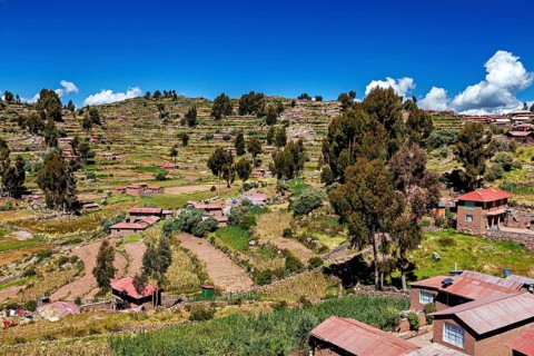 Hilly landscape with terraced fields and scattered farm houses under a blue sky, The countryside