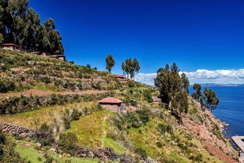 Terraces with huts and trees over a blue lake under clear skies, the countryside and farmhouses on