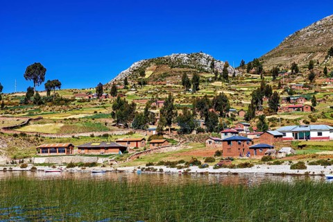 Idyllic village with lakeside farm houses and fields under blue skies, the countryside and