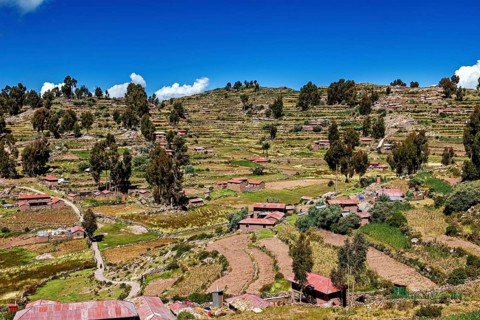 Terraced fields and farm houses stretch across green hills under blue skies, the countryside and