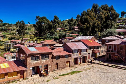 Historic buildings in an Andean village with a wide view of the surrounding area and a blue sky,