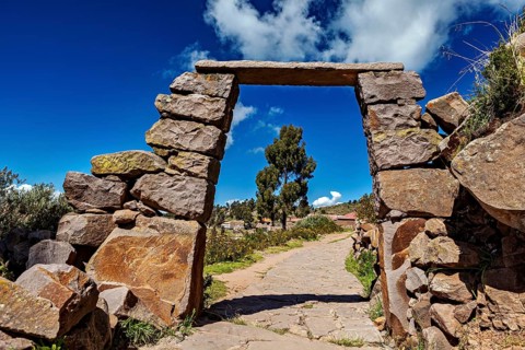 Rectangular stone archway with visible path below, blue sky in the background, stone gates on