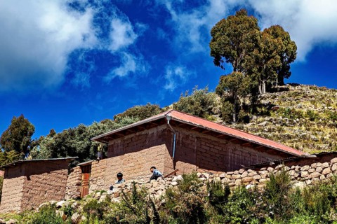 Rustic farm houses with two people and trees under a blue sky full of clouds, the countryside and