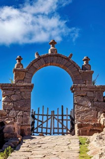 Stone gate under blue sky with some clouds, rustic appearance, stone gates on the island of Taquile